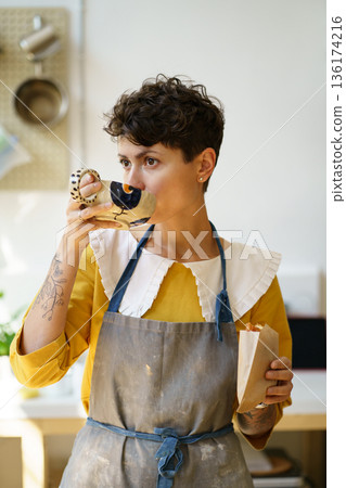 Female ceramist drink coffee and eat snack in art studio at break from master class produce pottery 136174216