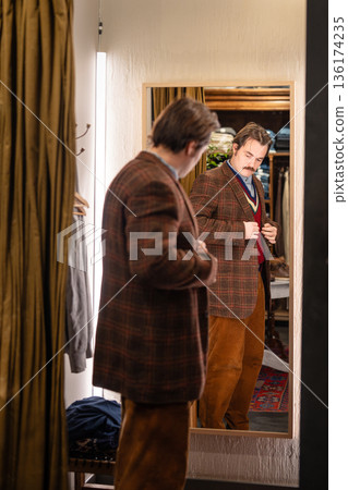 Man vintage clothing hunter shopping in second hand store, trying classy wool blazer in fitting room Man vintage clothing hunter shopping in second hand store, trying classy wool blazer in fitting room 136174235