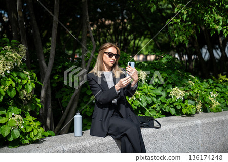 Trendy lady business influencer taking selfie picture on smartphone streaming video content online. Trendy lady business influencer taking selfie picture on smartphone streaming video content online. 136174248