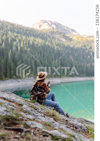 Young woman tourist uses a smartphone on the nature. Lifestyle, travel, tourism, active life. Young woman tourist uses a smartphone on the nature. Lifestyle, travel, tourism, active life. 136174250