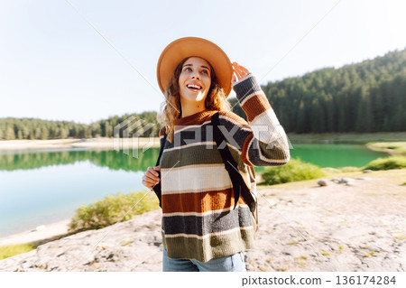 Young woman traveler enjoys fresh air and a beautiful view of the lake and mountains. Active life Young woman traveler enjoys fresh air and a beautiful view of the lake and mountains. Active life 136174284