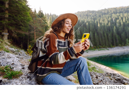 Young woman tourist uses a smartphone on the nature. Lifestyle, travel, tourism, active life. 136174291