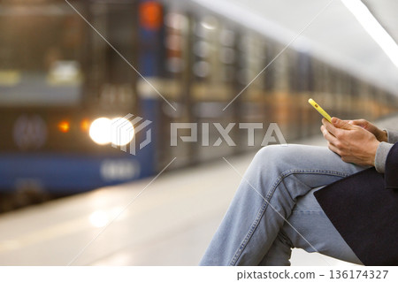 Man using smartphone subway, underground station, train on blurred background Man using smartphone subway, underground station, train on blurred background 136174327