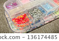 Close-up of colorful star-shaped sequins and glitter in a plastic organizer box for DIY craft projects. 136174485
