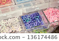 Delicate heart-shaped sequins in pastel colors stored in a plastic craft organizer for DIY designs. 136174486