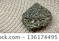 Raw pyrite crystal cluster with metallic shine on a neutral braided background for geology projects. 136174495