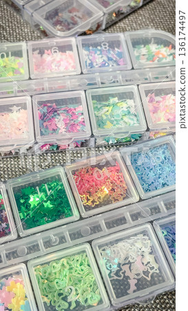 Top view of various pastel butterfly and star sequins in a multi-compartment craft storage organizer. Top view of various pastel butterfly and star sequins in a multi-compartment craft storage organizer. 136174497