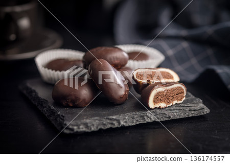 Dark chocolate truffles in the shape of coffee beans on black table. 136174557
