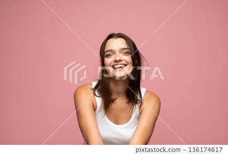 Young joyful woman with natural beauty smiling openly against pink background expressing happiness confidence and positive lifestyle mood Young joyful woman with natural beauty smiling openly against pink background expressing happiness confidence and positive lifestyle mood 136174617