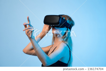 Woman using virtual reality headset with hand gestures, immersive VR technology and futuristic digital experience Woman using virtual reality headset with hand gestures, immersive VR technology and futuristic digital experience 136174704