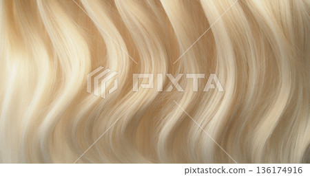 Close-up abstract texture of flowing blonde hair forming soft natural waves. Elegant curves, fine strands and warm tones create a luxurious beauty background ideal for cosmetic, fashion or haircare 136174916