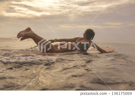 Young Woman Navigates Crashing Surf During Golden Hour Excitement 136175009