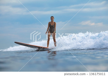 Lady At Sunrise Maintains Poise On Her Surfboard Surrounded By Surf And Spray 136175011