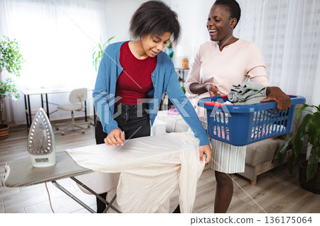 Mother and Daughter Ironing Clothes Together at Home Mother and Daughter Ironing Clothes Together at Home 136175064