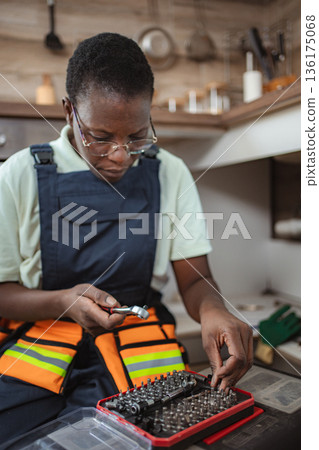 Female technician choosing right tool for fixing kitchen sink Female technician choosing right tool for fixing kitchen sink 136175068