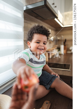 Happy toddler boy sharing apple in kitchen 136175074