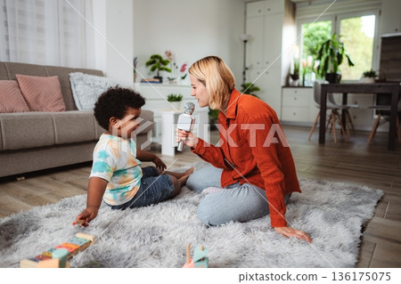 Mother and son playing with microphone at home 136175075