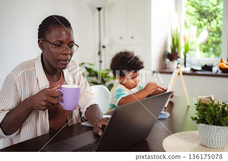Black mother working from home with child drawing Black mother working from home with child drawing 136175078