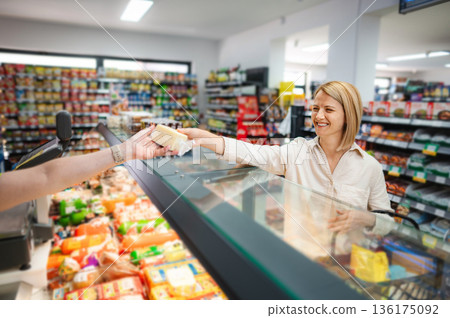 Woman buying cheese at deli counter in grocery store Woman buying cheese at deli counter in grocery store 136175092