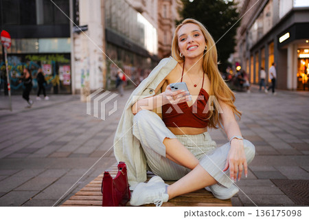 Young woman smiling, sitting on bench in Vienna, Austria 136175098