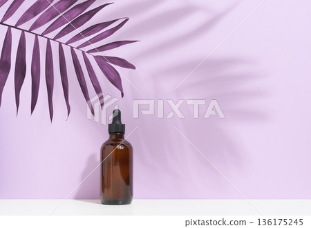 A dark brown glass bottle with a dropper dispenser on a soft lilac background A dark brown glass bottle with a dropper dispenser on a soft lilac background 136175245