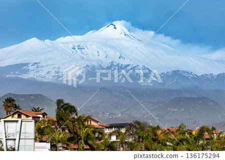 Snow capped volcano rising above town and palm trees creating unique travel and nature landscape. Snow capped volcano rising above town and palm trees creating unique travel and nature landscape. 136175294