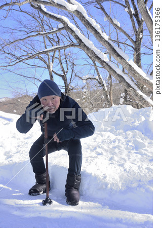 An elderly man doing rehabilitation using a walking stick on a snowy road An elderly man doing rehabilitation using a walking stick on a snowy road 136175366