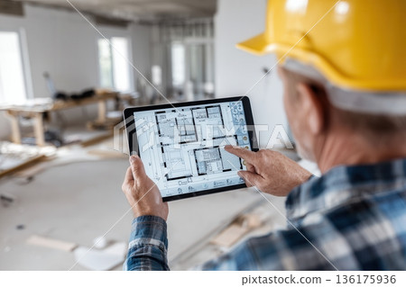 Construction worker reviewing blueprints on tablet at site Construction worker reviewing blueprints on tablet at site 136175936