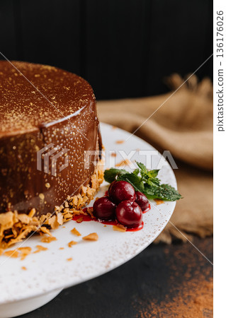 Chocolate glazed cake with cherries and mint on white plate, close up 136176026