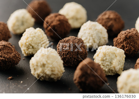 Macro coconut truffle with creamy center and cocoa truffles on dark slate Macro coconut truffle with creamy center and cocoa truffles on dark slate 136176030