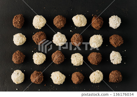Assorted coconut and cocoa truffles on black slate, flat lay Assorted coconut and cocoa truffles on black slate, flat lay 136176034