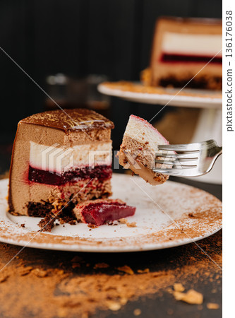 Fork with bite of layered chocolate mousse cake and berry jelly closeup 136176038