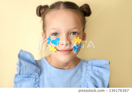 Portrait of a child with colorful puzzle and heart symbols on face, representing inclusion, social equality and support for people with Down syndrome, acceptance, diversity and empathy in modern socie Portrait of a child with colorful puzzle and heart symbols on face, representing inclusion, social equality and support for people with Down syndrome, acceptance, diversity and empathy in modern socie 136176367