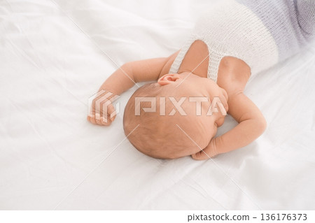 Peaceful sleeping newborn baby on white bed, symbol of childhood, care, safety, and International Childrens Day. Peaceful sleeping newborn baby on white bed, symbol of childhood, care, safety, and International Childrens Day. 136176373