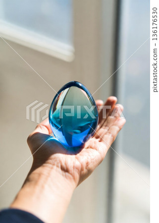 Place the beautiful egg-shaped object with a clear blue gradient in the palm of your hand and admire it. 136176530