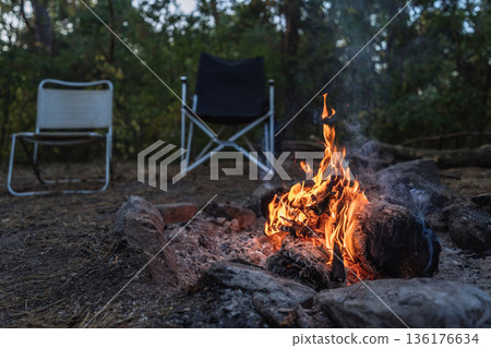 Campfire Burning at Forest Campsite with Empty Chairs Campfire Burning at Forest Campsite with Empty Chairs 136176634