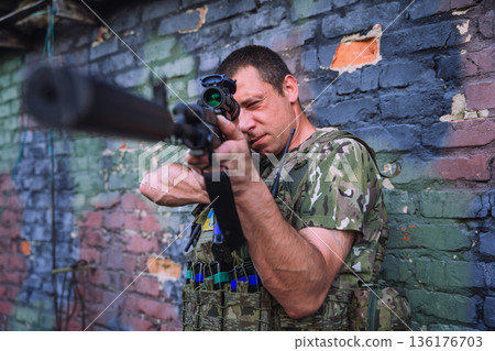 Ukrainian soldier aiming rifle during urban combat 136176703