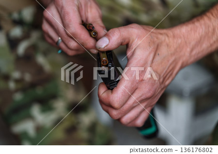 Hands loading ammunition into rifle magazine close up Hands loading ammunition into rifle magazine close up 136176802