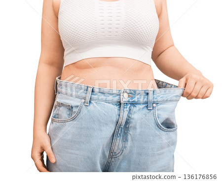 Cropped view of woman showing weight loss result in old jeans. Slim female pulling oversized pants at waist isolated on white background. Diet success concept. High quality photo Cropped view of woman showing weight loss result in old jeans. Slim female pulling oversized pants at waist isolated on white background. Diet success concept. High quality photo 136176856