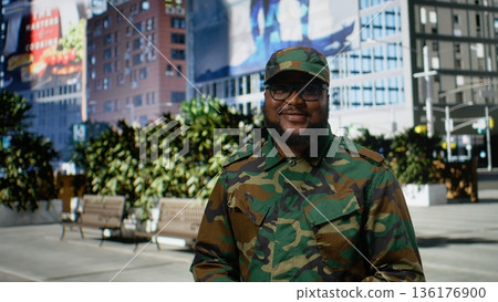 Confident african american soldier in uniform standing on a city street, showing disciplined posture and strong identity as he reflects dedication and honor with modern downtown vibes. Camera A. 136176900