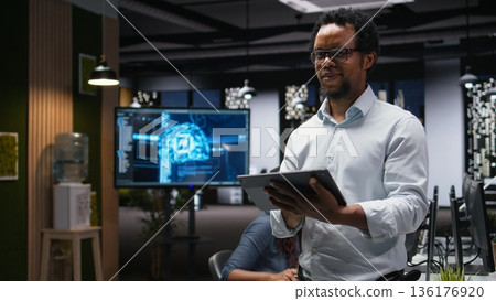 IT expert using tablet in office, working with AI programming languages. Programmer using device in company workplace to do artificial intelligence tech quality assurance 136176920