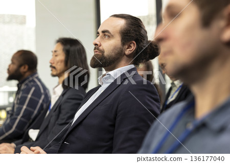 Adult CEO entrepreneur listening to startup presentation with diverse audience on chairs, international business conference created for networking. Participants attend professional event. Adult CEO entrepreneur listening to startup presentation with diverse audience on chairs, international business conference created for networking. Participants attend professional event. 136177040