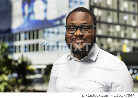 Portrait of black adult male standing out on a busy city street, expressive attitude and modern street style capturing the essence of contemporary urban lifestyle. Metropolitan scenery. Portrait of black adult male standing out on a busy city street, expressive attitude and modern street style capturing the essence of contemporary urban lifestyle. Metropolitan scenery. 136177044