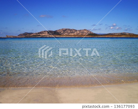 The breathtaking sea of Stintino near Olbia, Sardinia, reveals crystal-clear turquoise waters gently washing over fine white sand. Bathed in warm Mediterranean sunlight, this peaceful coastal 136177093