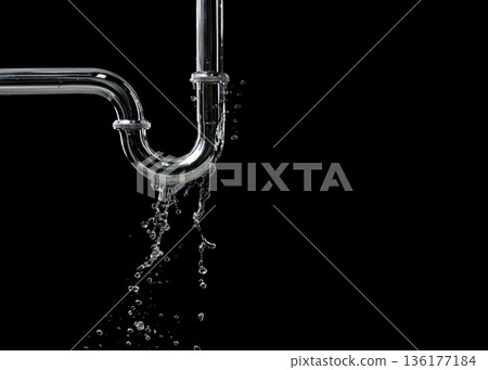 Drain leak water from pipe plumbing in bathroom as water clogged drop. Black background isolated. Leaking water from chromium stainless steel pipe under sink 136177184