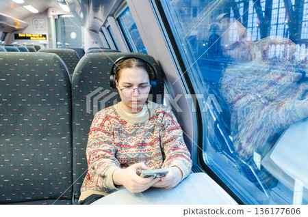 Smiling teenager girl with gallses and headphones in train Smiling teenager girl with gallses and headphones in train 136177606
