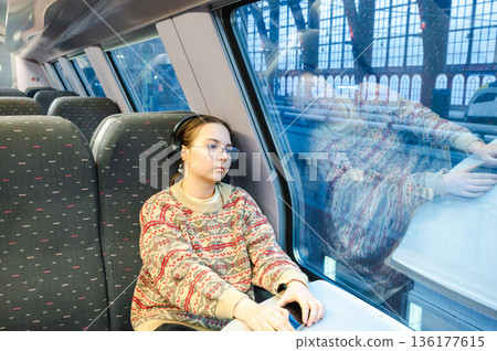 Smiling teenager girl with gallses and headphones in train Smiling teenager girl with gallses and headphones in train 136177615