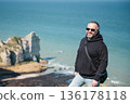 Man stands and look at cliffs and Waters of Etretat 136178118