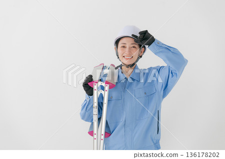 A woman in work clothes wearing a helmet A woman in work clothes wearing a helmet 136178202