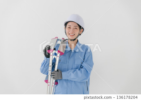 A woman in work clothes wearing a helmet 136178204